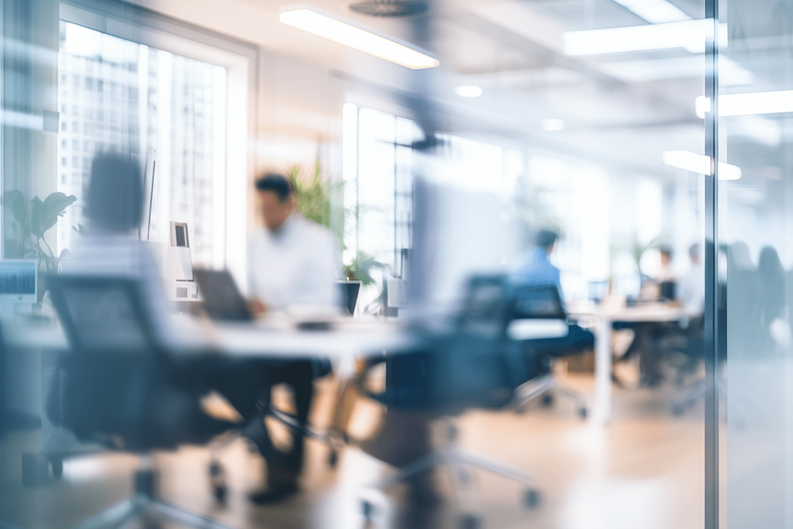 Blurred office with people working behind glass wall